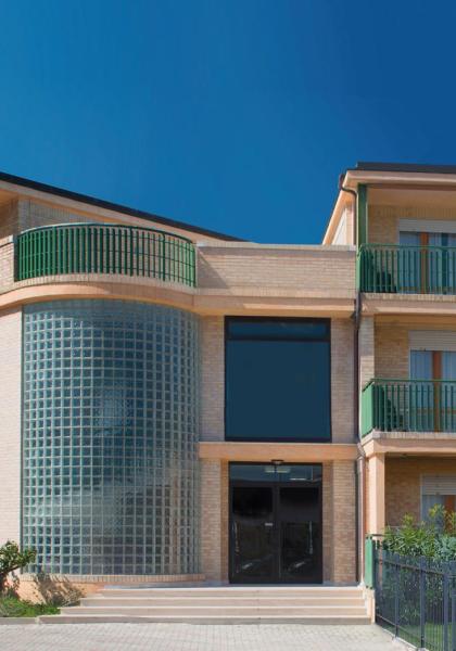 Modern building with green balconies and glass walls.