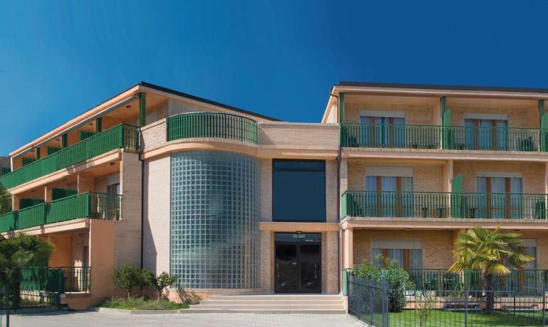 Modern building with green balconies and glass walls.