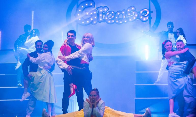 Dance show inspired by Grease with colorful lights.